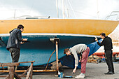 Männer streichen gemeinsam ein Boot