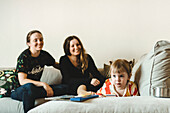 Girls on sofa looking away, mothers on background