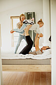 Father playing with daughters in bedroom