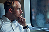 Mann schaut durch ein Zugfenster