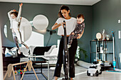 Woman carrying toddler and vacuum cleaning room