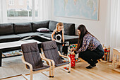 Smiling girl vacuum cleaning living room