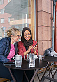 Female friends having coffee in outdoor cafe