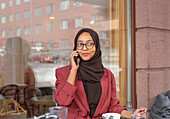 Lächelnde Frau im Café, die über ihr Handy spricht