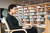 Frau mit Laptop in der Bibliothek