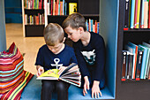 Boys looking at book in library