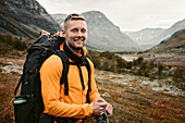 Smiling man carrying backpack in mountains