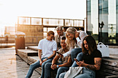 Smiling friends sitting on bench together