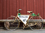 Old bicycle with recycling sign against wooden wall