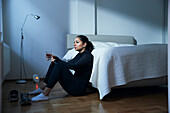 Woman sitting on bedroom floor