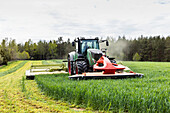 Traktor mäht Gras auf einem Feld