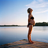 Schwangere Frau stehend auf Steg am See