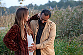 Mann hält Hände auf dem Bauch einer schwangeren Frau