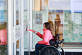 Frau im Rollstuhl öffnet Tür