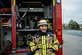 Smiling firefighter in front of fire engine