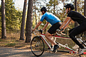 Visually impaired female triathlete training on tandem bicycle with her guide and coach
