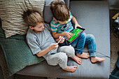Boys using digital tablet on sofa