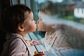 Baby-Mädchen schaut durch ein Fenster