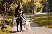 Sehbehinderte Frau steht mit Blindenhund im Park