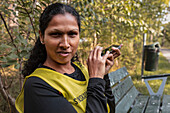 Visually impaired woman sitting on bench and using cell phone