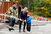 Mother with son using fire hose