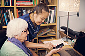 Ältere Frau und Betreuerin telefonieren mit Handy