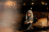 Reife Frau im Cafe liest Buch