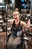 Glückliche Frau im Rollstuhl beim Training im Fitnessstudio