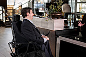 Geschäftsmann im Rollstuhl in der Hotellobby