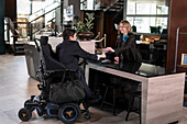 Geschäftsmann im Rollstuhl an der Hotelrezeption