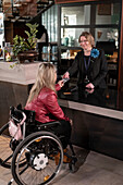 Frau im Rollstuhl im Gespräch mit der Rezeptionistin