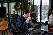 Geschäftsmann im Café schaut auf ein digitales Tablet