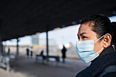 Woman wearing face mask on train station platform