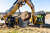 Excavator removing large stone