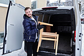 Lächelnder Mann beim Abladen von Möbeln aus einem Lieferwagen
