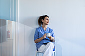 Krankenschwester sitzt auf einem Stuhl und hält einen Becher