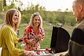 Friends preparing food on barbecue and drinking wine