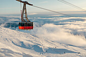 Ski lift above clouds and ski slope