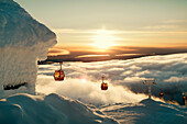 Ski lifts above clouds at sunset