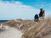 Frau mit Kinderwagen auf Sanddünen stehend