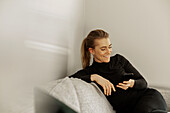 Smiling woman on sofa using cell phone