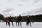 Freunde spielen Hockey auf gefrorenem See