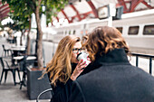 Man and woman drinking coffee at train station