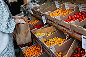 Frau im Geschäft wählt Tomaten aus