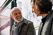 Smiling man talking to woman at bus stop