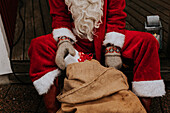 Person wearing Santa costume holding Christmas present