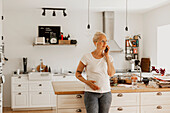 Woman talking via phone in kitchen