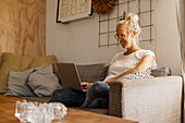 Smiling woman using laptop on sofa