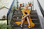 Frau sitzt auf einer Treppe und benutzt ein Mobiltelefon
