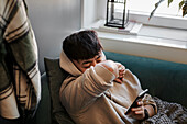Kranker Mann auf Sofa mit Mobiltelefon
